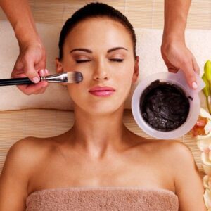 A woman getting her face washed with clay