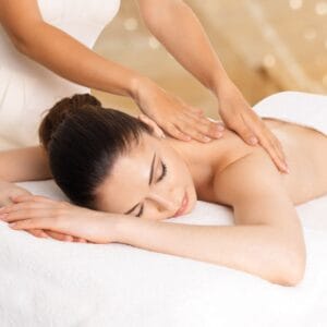 A woman getting her back touched by a masseuse.