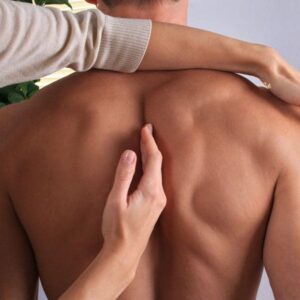 A person is holding their back while another person touches his shoulder.
