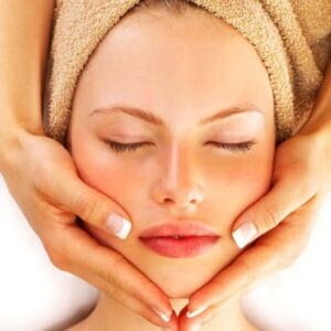 A woman getting her face washed with towel on head.