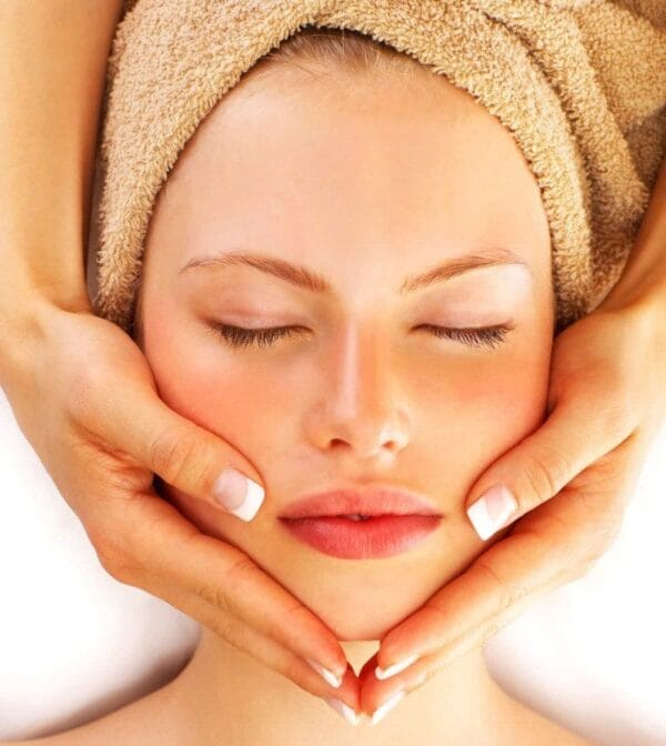 A woman getting her face washed with towel on head.